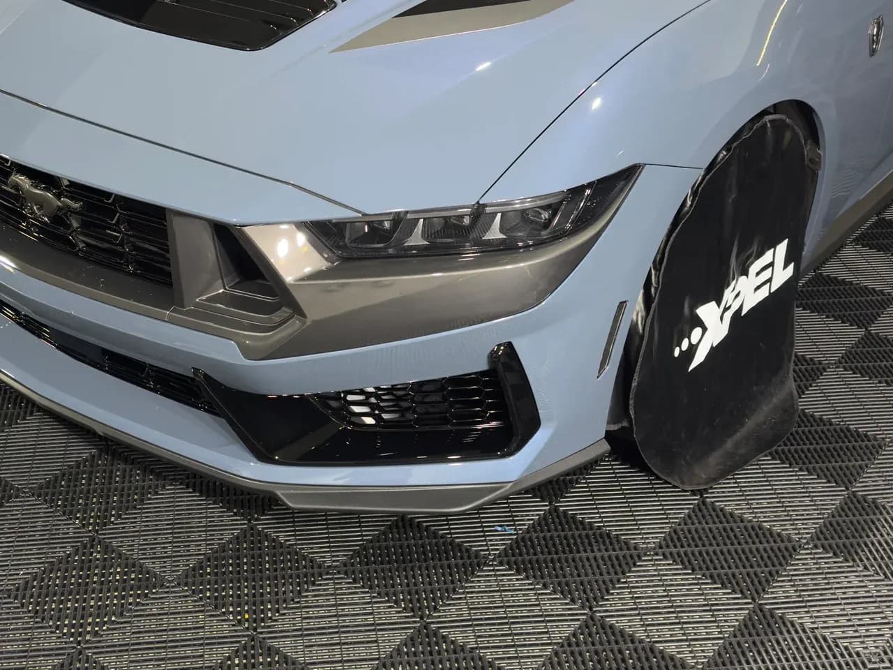 Paint protection film on a Ford Mustang bonnet, with an XPEL branded wheel cover
